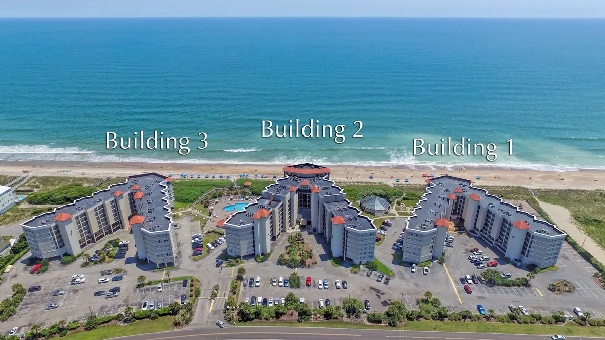 Here, three architecturally distinct buildings overlook a spacious swimming pool area, just steps from the sandy beach. The poolside loungers and proximity to the ocean highlight the seamless blend of indoor comfort and outdoor adventure.